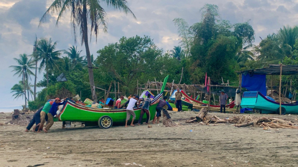 warga yang baru pulang melaut dibantu oleh yang lain.